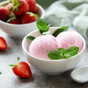 Helado de fresa en tazón con fresas frescas y menta
