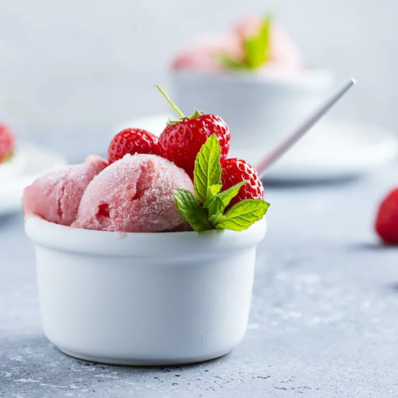 Copa de helado de fresa con frambuesas y menta